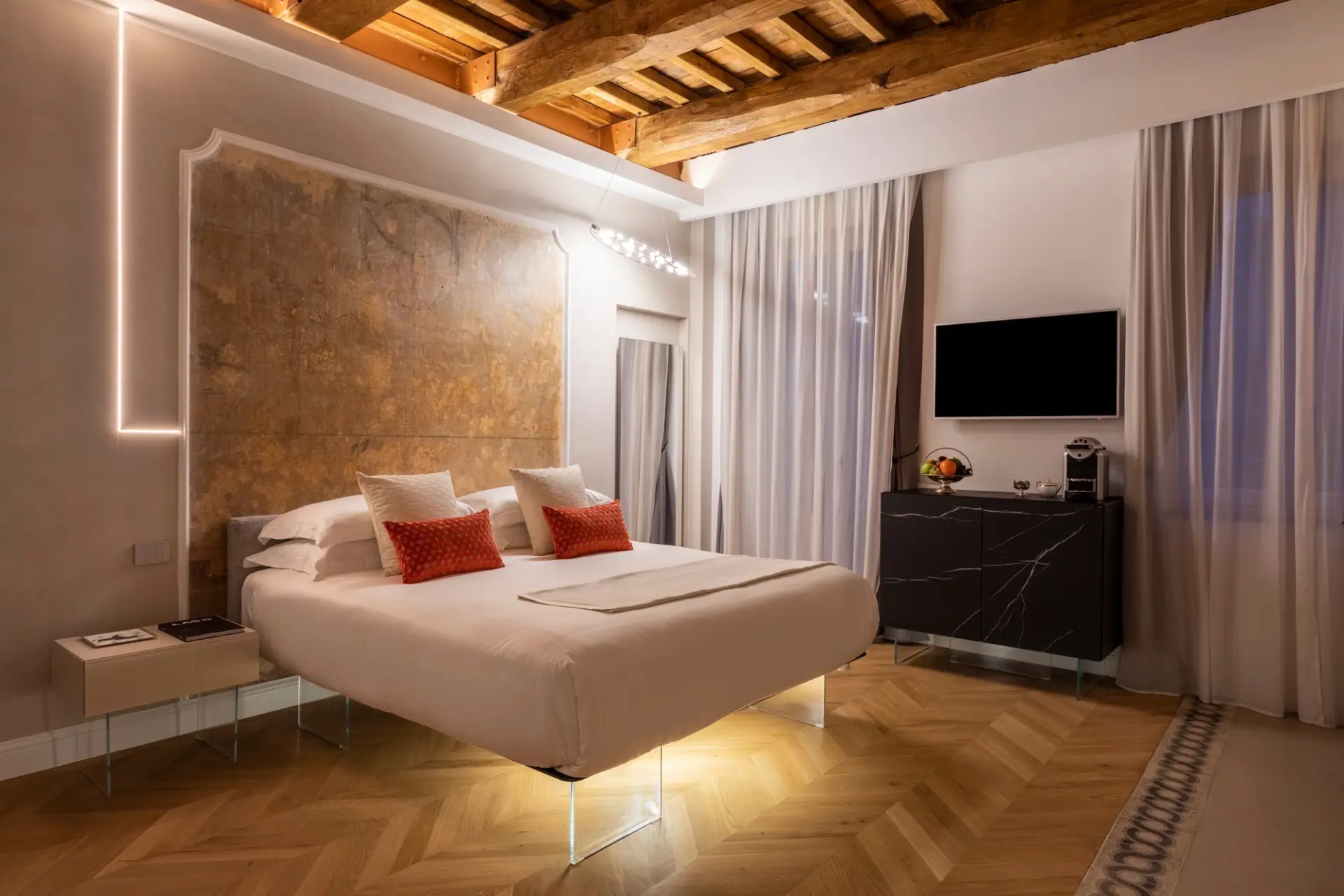 Ambiente con soffitto ligneo originale recuperato Suite con travi a vista e testata letto in tessuto