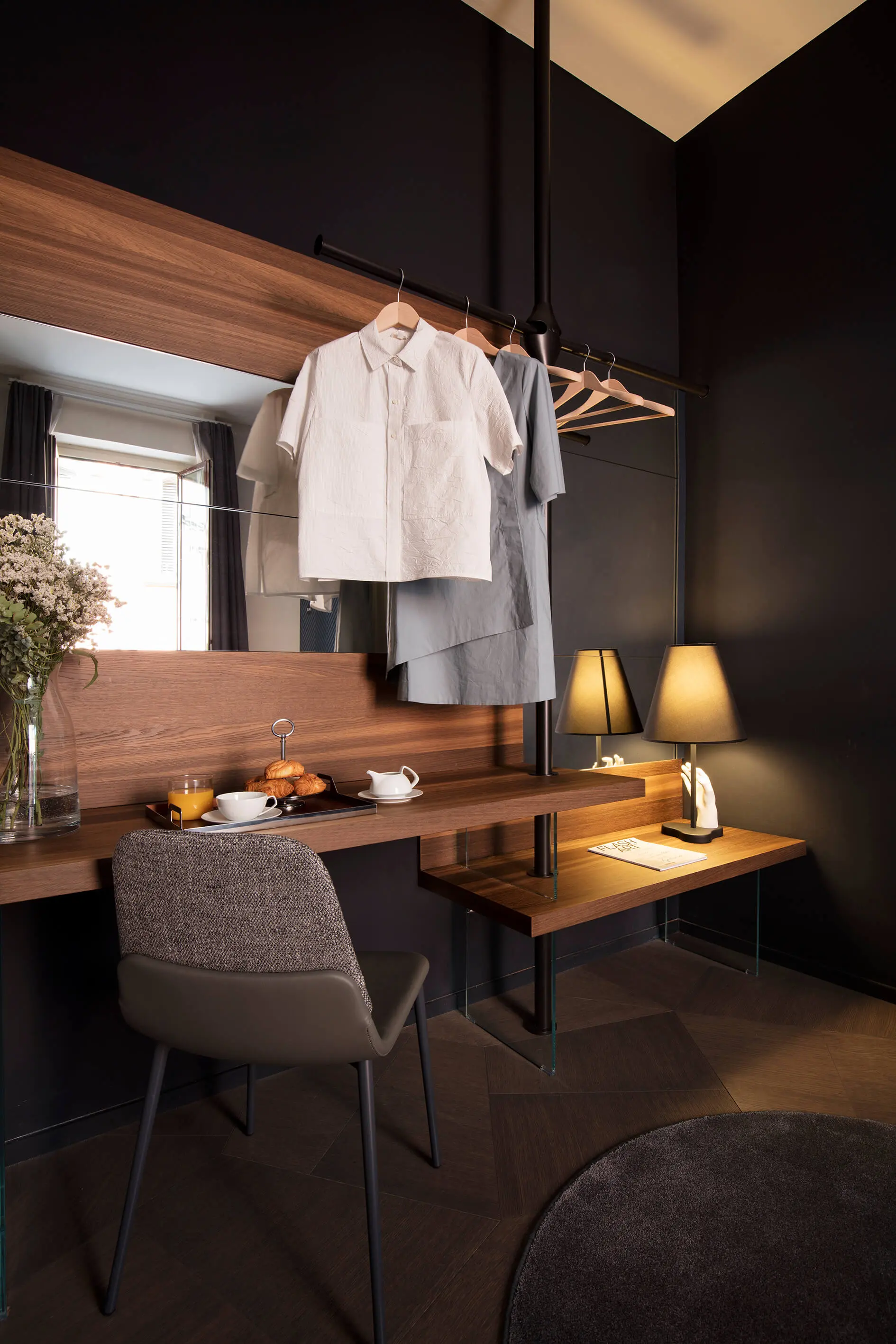 Ambiente con palette scura e dettagli in ottone Suite con toni scuri, appendiabiti a soffitto e scrittoio